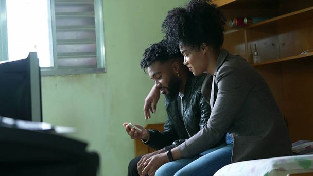 Una coppia africana seduta insieme a fissare il cellulare - Foto, immagini