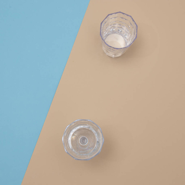 Two glasses stand alone on the beach by the sea. Minimal flat lay scene. - Fotoğraf, Görsel