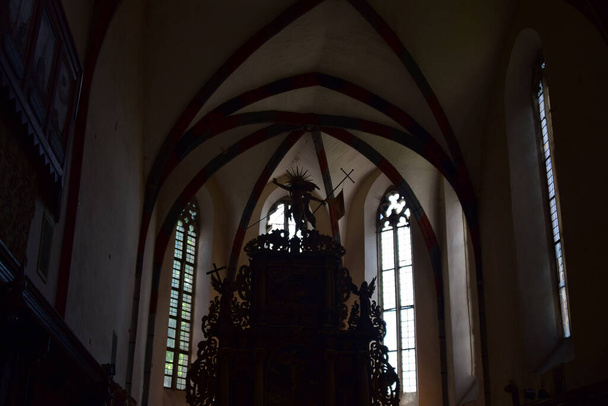 binnen in de katholieke kerk van Sighisoara met orgel, bogen, romeinse rozetten, klokkentoren met beelden met Christus en Roemeense soldaten in een katholieke sfeer zo belangrijk als militaire architectuur - Foto, afbeelding