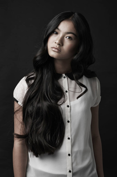 Long-haired beauty. Studio shot of a beautiful young woman posing against a black background. - Foto, Imagem
