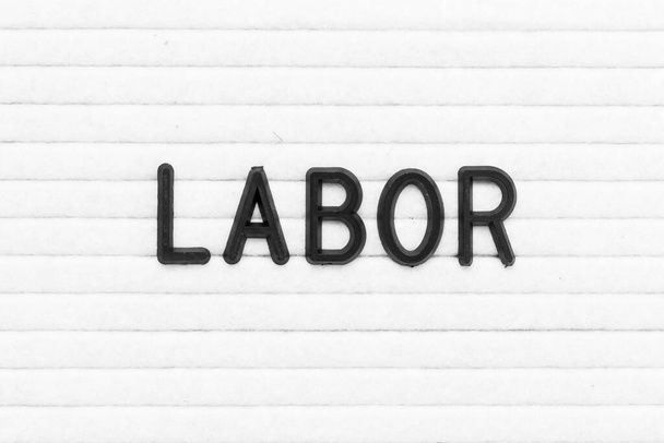 Black color letter in word labor on white felt board background - Photo, Image
