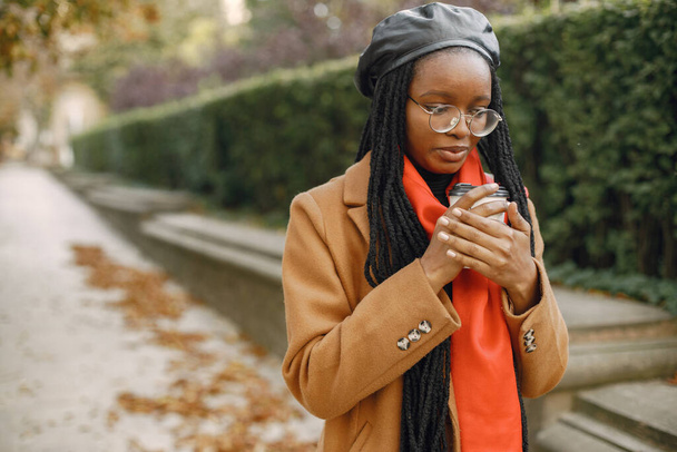Young black woman in a coat drinking coffee outside - Photo, image