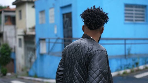Back of young black man crossing street in urban city - Фото, зображення