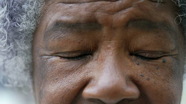 A black older woman closing eyes in meditation macro eyes closeup - Foto, immagini