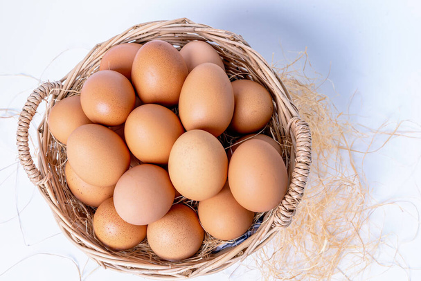 Fresh eggs collected inside wicker basket, suitable as a food ingredient. Fresh eggs from quality organic farms isolated on white background. Healthy food concept - Fotografie, Obrázek