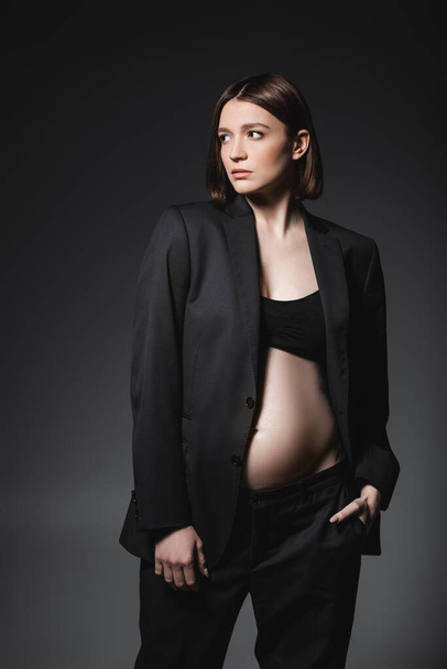 Fashionable pregnant woman in jacket posing isolated on dark grey  - Фото, зображення