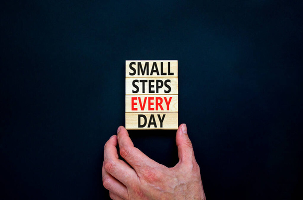 Small steps every day symbol. Concept words Small steps every day on wooden blocks. Businessman hand. Beautiful black table black background. Small steps every day business concept. Copy space. - Photo, Image