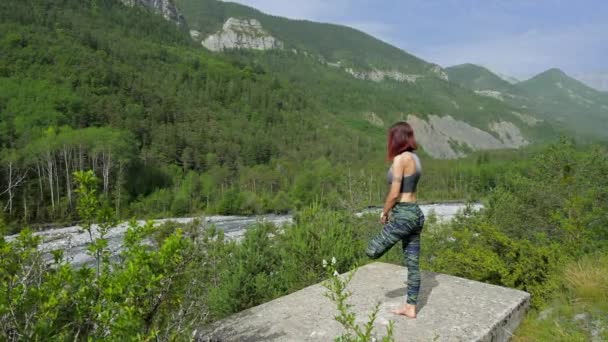 女性は山の中の川の近くでヨガをやってフィット - 映像、動画