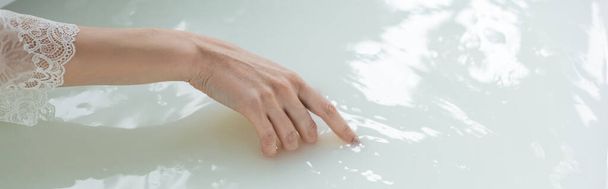 Cropped view of woman touching water in bathtub, banner  - Foto, Bild