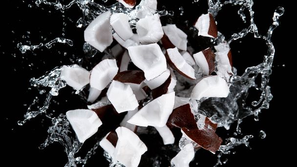 Freeze motion of coconuts in water splash. Isolated on Black Background. - Foto, Imagen