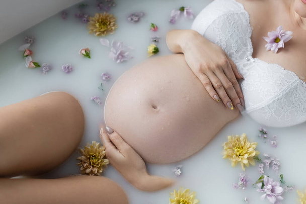 妊娠中の女性が花やミルクと一緒にお風呂に入る様子  - 写真・画像