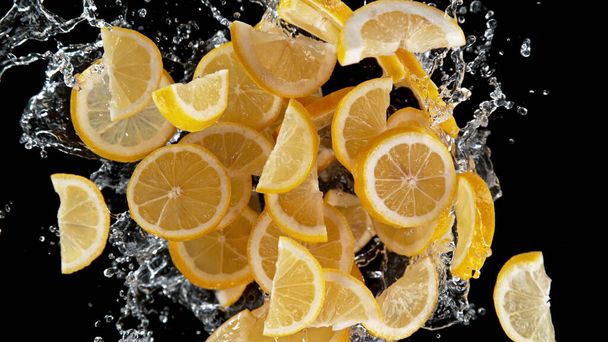 Freeze motion of sliced lemons in water splash. Isolated on Black Background. - 写真・画像