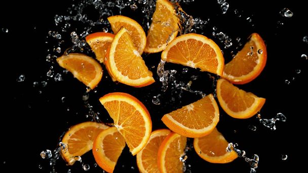 Freeze motion of sliced oranges in water splash. Isolated on Black Background. - Foto, afbeelding