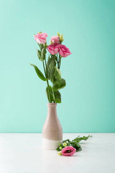 Pink flowers eustoma in vase against light background - Fotó, kép