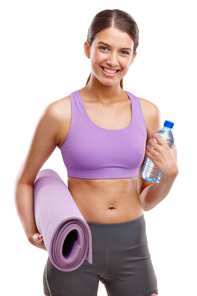Im ready for my workout. Shot of a beautiful young woman holding an exercise mat and a bottle of water. - 写真・画像
