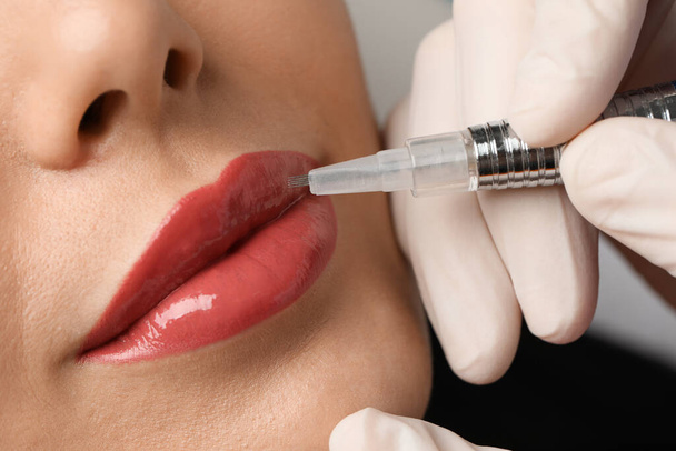 Young woman undergoing procedure of permanent lip makeup in salon, closeup - Foto, imagen