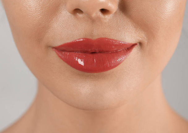 Young woman with permanent lip makeup on grey background, closeup - Valokuva, kuva