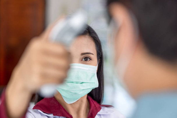 Farmacéuticas asiáticas miden la fiebre antes de visitar la farmacia Tailandia de cerca y enfoque selectivo virus corona covid-19 concepto  - Foto, imagen