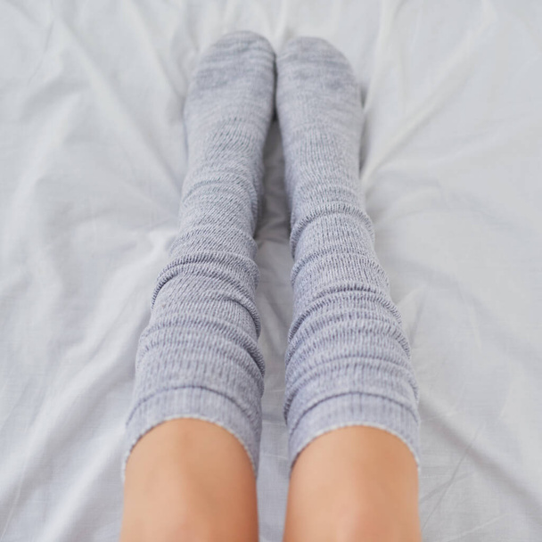 Socks are a must have for stay at home days. Cropped shot of a woman wearing grey socks in bed. - Фото, изображение