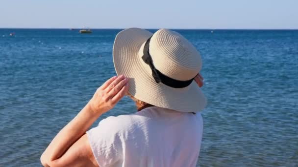 krásná 50 letá žena v slamáku a sluneční brýle na modrém mořském pozadí. Léto, dovolená, dovolená, aktivní důchodci - Záběry, video