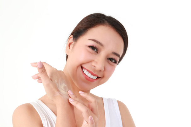 Bella donna asiatica che applica la crema per la pelle sul braccio per migliorare la sua bellezza. Si prende cura della sua salute della pelle per essere liscia, luminosa, sana, naturale. concetto di bellezza assistenza sanitaria. Fondo bianco. - Foto, immagini