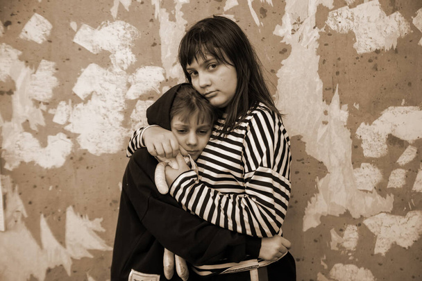 Kaksi pientä tyttöä seisoo syleilyssä tuhottu muuri ja peloissaan, käsite viimeisimmät uutiset maailmassa Venäjän hyökkäys Ukrainaan - Valokuva, kuva