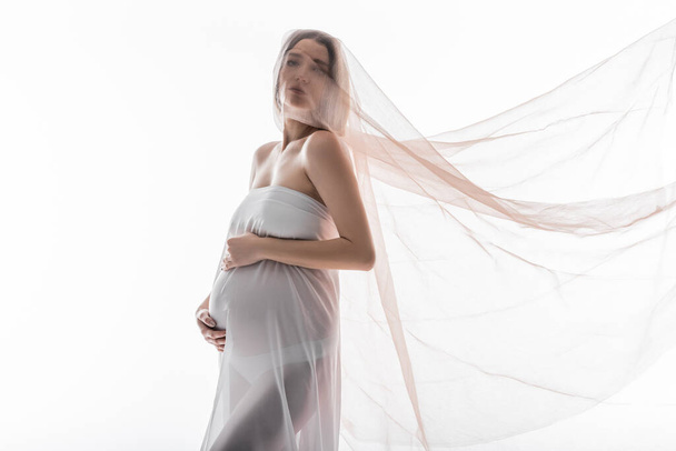 Mulher grávida em pano olhando para a câmera isolada no branco  - Foto, Imagem