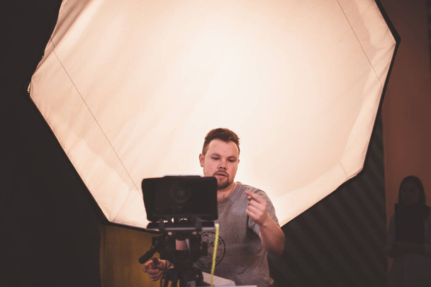 Operatőr kamerával a kezében a forgatáson. Film-, reklám- vagy TV-sorozat forgatásán dolgozó professzionális videós. Filmkészítési folyamat zárt térben, stúdióban - Fotó, kép