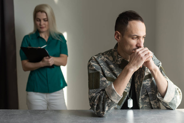 Naispuolinen lääkäri ja huolestunut sotilasupseeri keskustelemassa ongelmista, joita hänellä on psykoterapian aikana
. - Valokuva, kuva