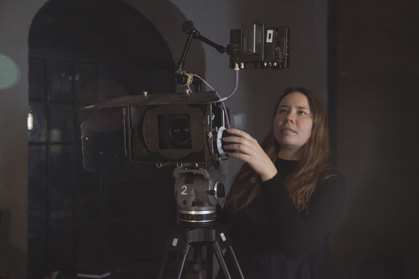 Egy fiatal női rendező a munka mögött egy film kamera egy film forgatás, reklám vagy közvetítés. Modern fotózás technológia. - Fotó, kép
