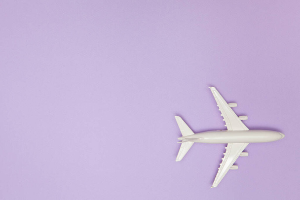 Airplane model. White plane on purple background. Travel vacation concept. Summer background. Flat lay, top view, copy space. - 写真・画像