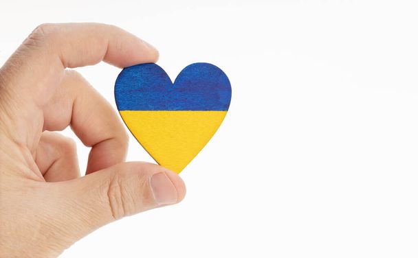 Kalp şeklinde bir Ukrayna bayrağını tutan el. Beyaz arka plan. Boşluğu kopyala - Fotoğraf, Görsel
