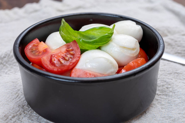 Cuisine italienne, salade de caprese savoureuse aux tomates cerises rouges, fromage mozzarella blanc et feuilles de basilic vert - Photo, image