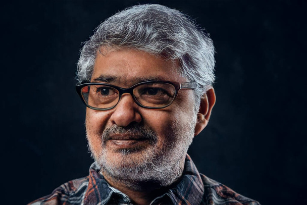 Headshot of hindu grandfather with glasses against dark background - Foto, afbeelding