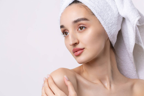 Beautiful girl with thick eyebrows and perfect skin at white background, towel on head, beauty photo. - Photo, Image