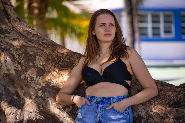 Beautiful girl leaning against a palm tree at Miami Beach South Beach - Fotoğraf, Görsel