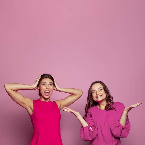 Дві щасливі здивовані жінки сміються, кричать і святкують успіх на рожевому фоні з копіювальним простором для тексту
 - Фото, зображення