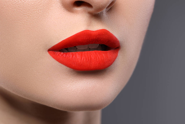 Young woman with beautiful red lips on grey background, closeup - 写真・画像