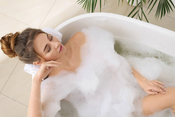 Beautiful woman enjoying bubble bath at home, above view - Фото, зображення