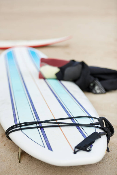 Pronto para a viagem. Uma prancha de surf e um fato de mergulho deitados na areia da praia. - Foto, Imagem