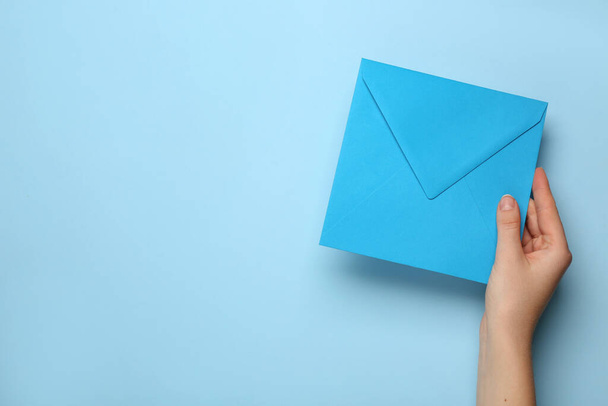 Woman holding envelope on light blue background, top view. Space for text - Foto, imagen