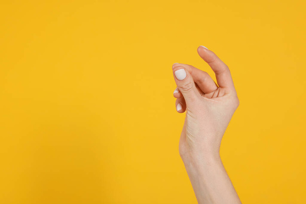 Vrouw knipt vingers op gele achtergrond, close-up van de hand. Ruimte voor tekst - Foto, afbeelding