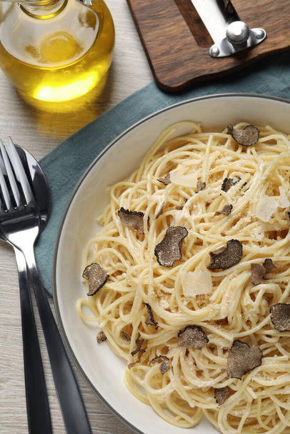 Tasty spaghetti with truffle served on wooden table, flat lay - Foto, imagen