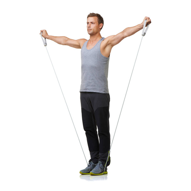 Extending his arms. A fit young man working out with a resistance band while isolated on a white background. - Фото, изображение