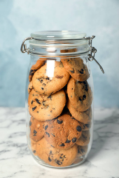 Delicious chocolate chip cookies in glass jar on white marble table - Foto, Imagen