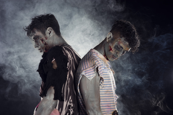 Two male zombies back to back on black smoky background - Photo, image