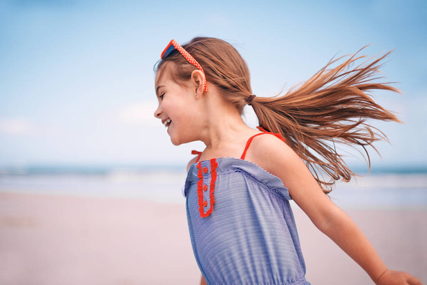 Наслаждаюсь свободой молодежи. Снимок маленькой девочки, бегущей вдоль пляжа. - Фото, изображение