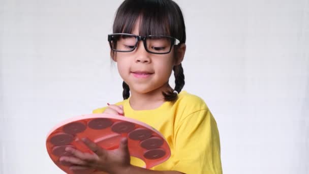 Roztomilá holčička drží štětec malování imaginární obrázek na bílém pozadí ve studiu. koncepce vzdělávání a představivosti - Záběry, video