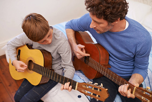 Getting it right together. Shot of a father teaching his son the guitar. - Фото, изображение