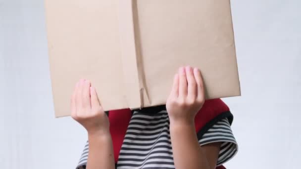 Mosolygó iskoláslány nyári ruhában, hátizsákkal, fehér hátterű könyvekkel a stúdióban. Vissza az iskolába - Felvétel, videó